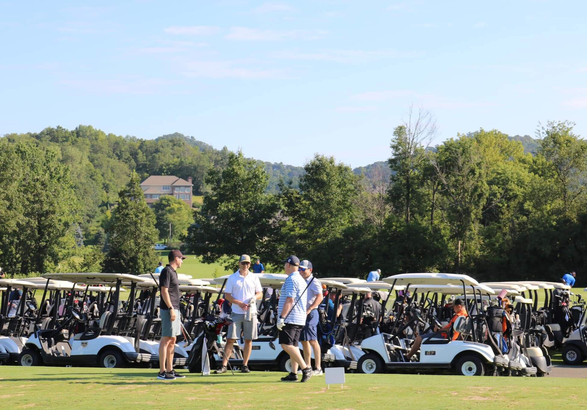 Golf carts with a group of people talking in the front